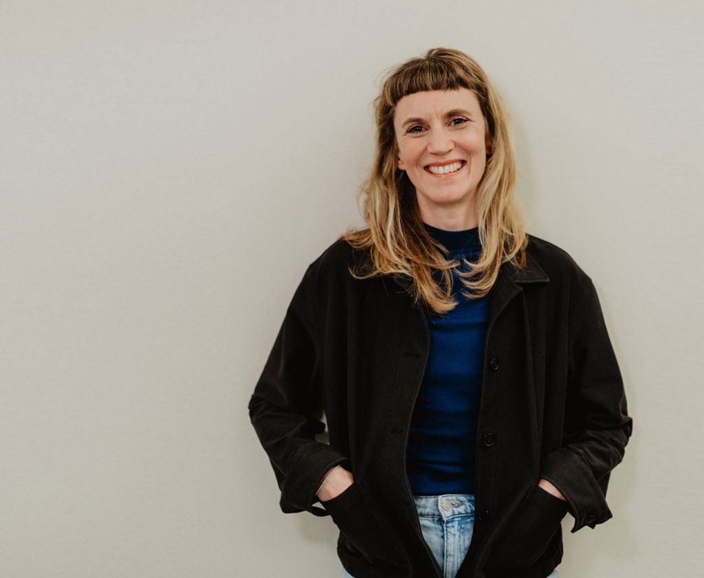 Business Porträt Jasmin Jochum lächelnd vor heller Wand